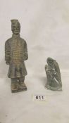A carved stone figure of a terracotta soldier and a carved soapstone lizard.