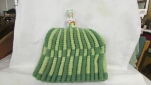 A knitted tea cosy with doll top.