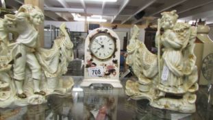 A pair of porcelain figures and a china mantel clock.