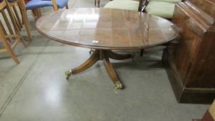 An oval coffee table with glass top on brass lion paw casters.