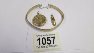 A 9ct gold locket, a 9ct gold bangle and a 9ct gold shoe charm,