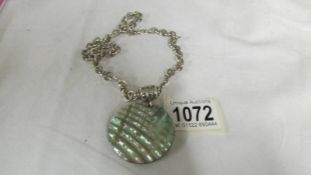 A silver chain with attached mother of pearl pendant, total weight 61 grams.