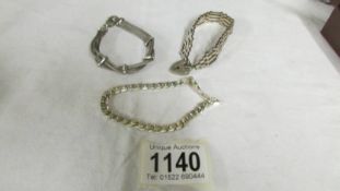 A silver gate bracelet and two other silver bracelets.