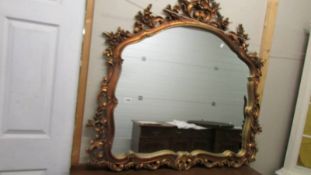 An ornate gilt framed overmantel mirror.