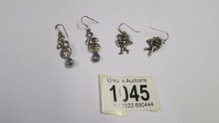 A pair of silver Cupid earrings and another pair of silver earrings.