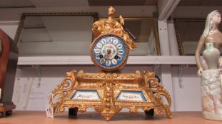 A French gilded mantel clock with porcelain panels complete with key and pendulum.