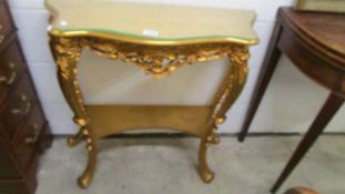 A gilded console table with glass top.