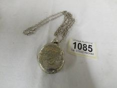 A silver engraved locket on a silver chain.