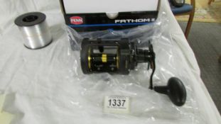 A boxed PENN Fathom level wind fishing reel.