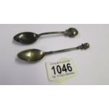 A golf related silver teapoon and another silver teaspoon.