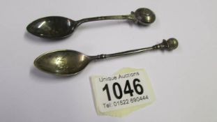 A golf related silver teapoon and another silver teaspoon.