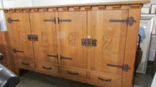 A light oak carved four door four drawer cupboard. (Very Heavy.) Collect only.