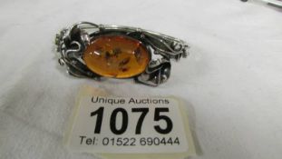 An oval amber and silver fancy work bracelet.
