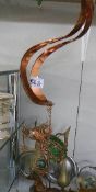 A hanging brass and glass frog wind chime.