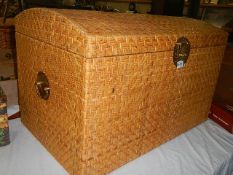 A dome topped wicker trunk with brass handles.