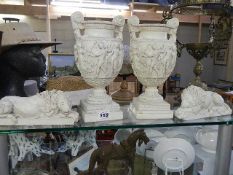 A pair of resin urns and a pair of resin lions.