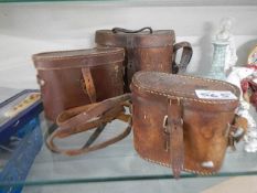 Three old leather binocular cases.