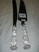 A pair of cake servers with cut glass handles.
