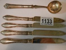 A silver sugar spoon and four silver handled knives.