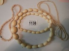 A large bead bone necklace and two coral necklaces.