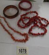 A red coral necklace, a pink coral necklace, two bangles and a similar ring.