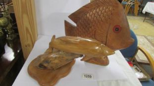 A carved wood dolphin and another carved fish.