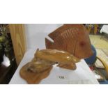 A carved wood dolphin and another carved fish.