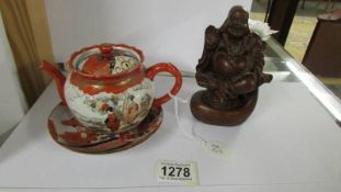 A Chinese teapot on saucer and a figure of a Buddha,