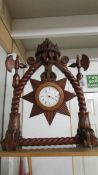 A carved clock having carved crowns, axes etc., with a quartz movement.