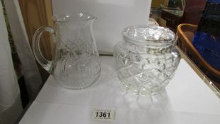 A cut glass biscuit jar and a cut glass jug.