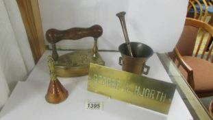 A brass pestle & mortar, a brass flat iron, a brass bell and a brass door sign.