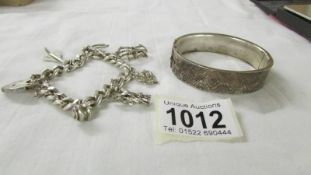 A silver bangle and a silver charm bracelet. 65 grams.