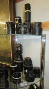 Two shelves of vintage camera lenses.