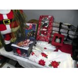 A selection of Christmas items including tablecloth, napkins, singing Santa, Christmas box etc