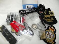 A selection of military cloth and metal badges, mostly reproduction
