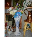A tall blue and white vase with artificial flowers.