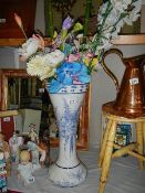 A tall blue and white vase with artificial flowers.