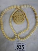 A bone necklace with cellulose carved mirror pendant.