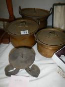 A set of three brass pans and a candle holder.