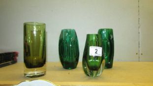 A pair of green glass vases and two other green glass items.