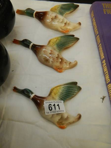 A set of three ceramic flying ducks.