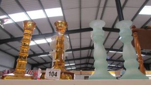 Two amber coloured candlesticks, a pair of green glass candlesticks and 2 white candlesticks.