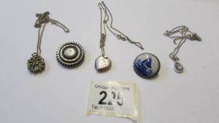 Three silver pendants and two silver brooches.