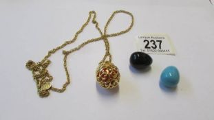 A Yellow metal opening egg pendant on chain with three interchangable coloured eggs,