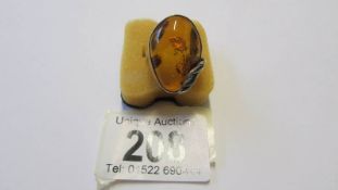 A large silver ring with large amber coloured stone in art deco design.