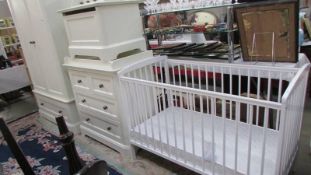 A suite of babies bedroom furniture comprising wardrobe, chest of drawers, toy box, cot, coat hooks.