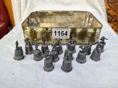 A quantity of pewter thimbles with characters on top.