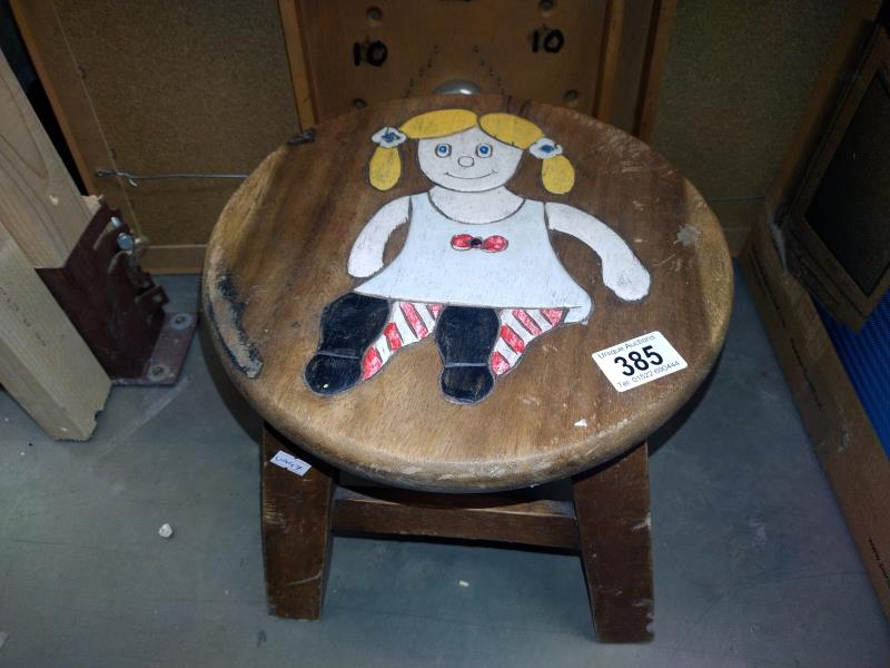 A child's stool with painted relief carving of a doll on top. Diameter 30cm, Height 27cm