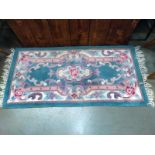 A pink and green far-eastern floral style rug. 132cm x 61cm