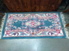 A pink and green far-eastern floral style rug. 132cm x 61cm